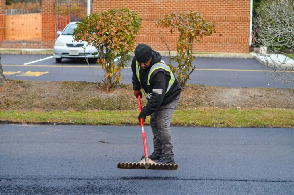paving contractor raking asphalt to even out new asphalt pavement installation in new jersey