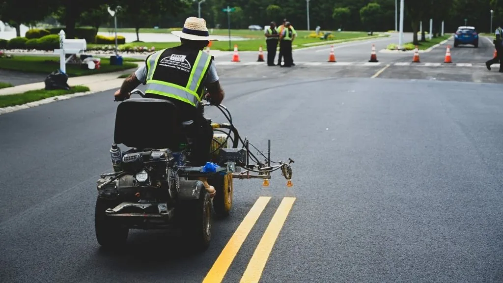 paving company employee on a machine performing a roadway striping project